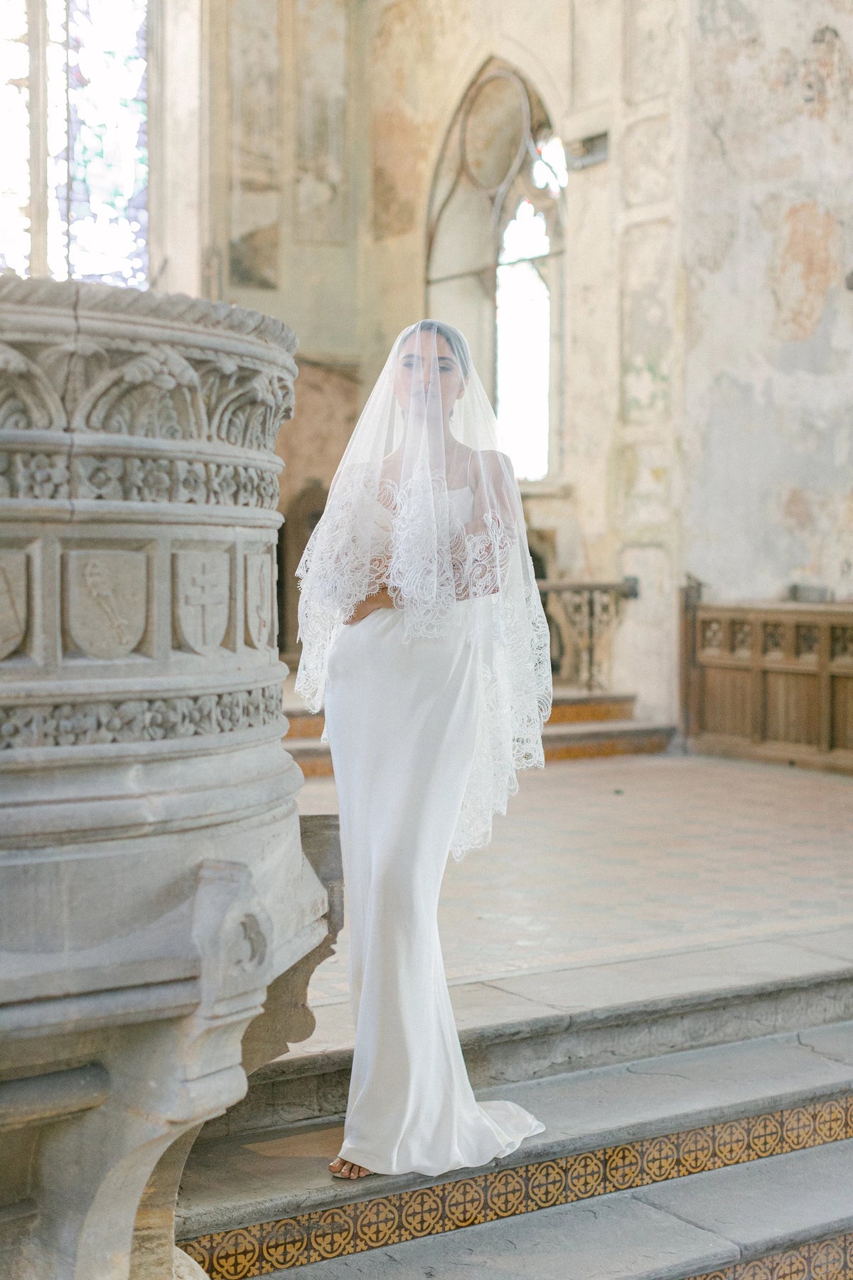 Ambra ivoorkleurige bruidssluier van Hanna Peters × Gibson Bespoke, met handgestikt Italiaans kant, abstract gebogen kantmotief, fijne wimperranden en transparante Italiaanse tule.