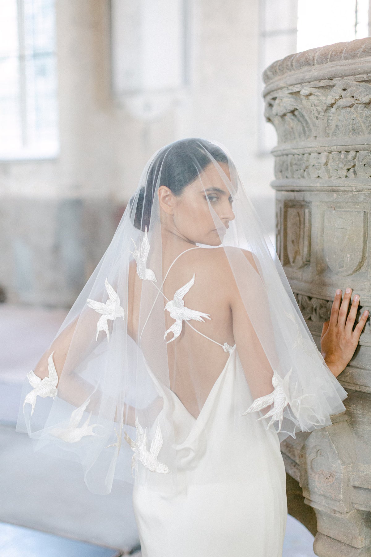 Passerine ivoorkleurige bruidssluier van Hanna Peters × Gibson Bespoke, gemaakt van transparante Italiaanse tule met handgenaaide zwaluwen van zuivere zijde en een cirkelvormige watervalvalling.