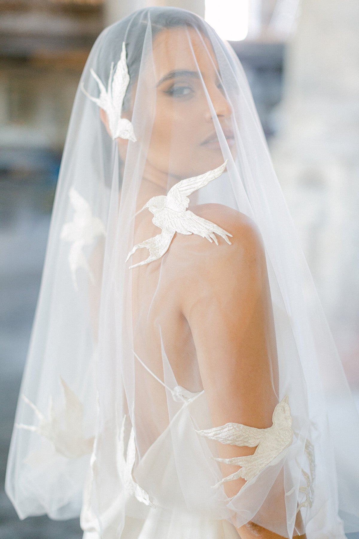 Passerine ivoorkleurige bruidssluier van Hanna Peters × Gibson Bespoke, gemaakt van transparante Italiaanse tule met handgenaaide zwaluwen van zuivere zijde en een cirkelvormige watervalvalling.