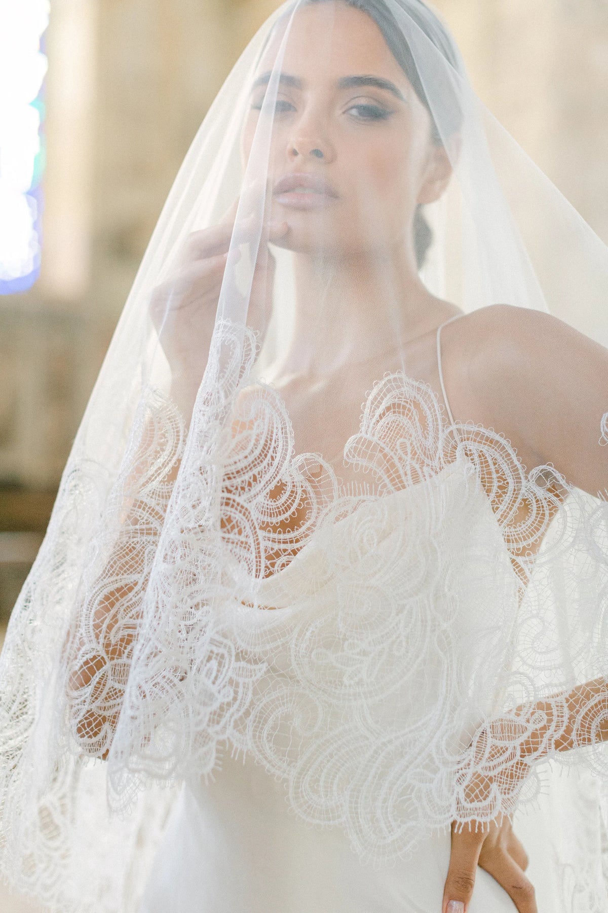 Ambra ivoorkleurige bruidssluier van Hanna Peters × Gibson Bespoke, met handgestikt Italiaans kant, abstract gebogen kantmotief, fijne wimperranden en transparante Italiaanse tule.