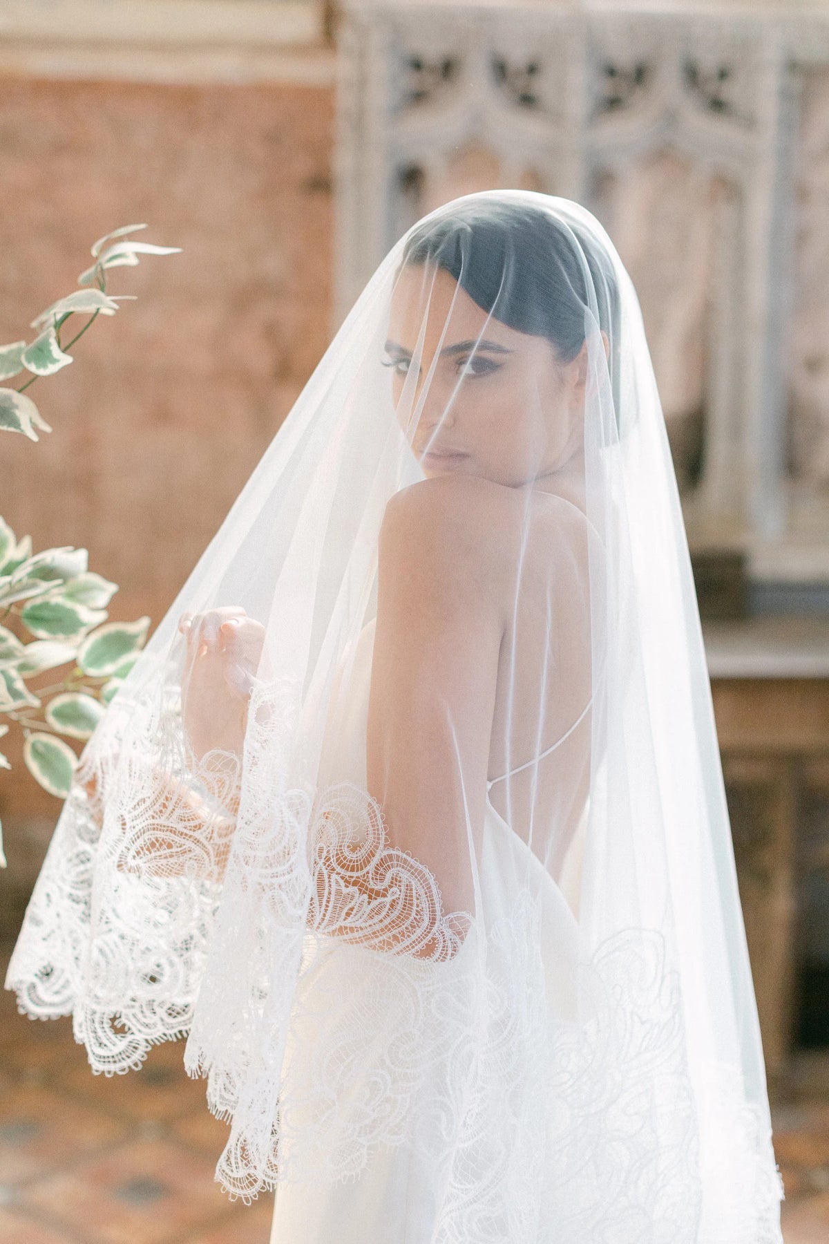 Ambra ivoorkleurige bruidssluier van Hanna Peters × Gibson Bespoke, met handgestikt Italiaans kant, abstract gebogen kantmotief, fijne wimperranden en transparante Italiaanse tule.